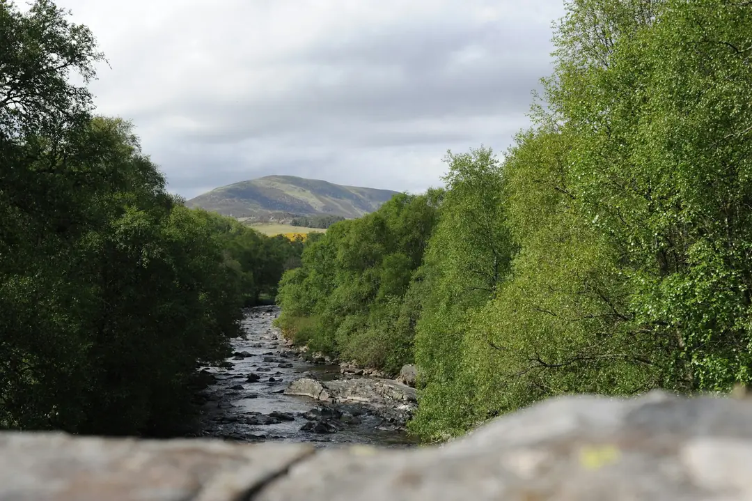 The River Isla running over stones in Glen Isla, with hills at the head of the glen