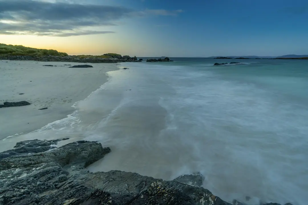 Pale sand and long Atlantic swell on a beach on Iona in evening light