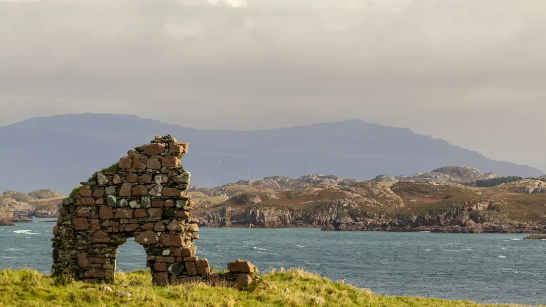 A ruined stone arch on Iona with the Sound of Iona and the hills of Mull behind